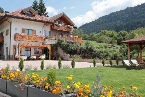 a house in a garden with flowers in the foreground at Agriturismo Ai Castioni in Molveno