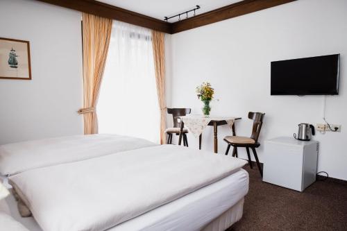 a hotel room with two beds and a table with a television at Pension Baranek - Baranek Resorts in Kaprun