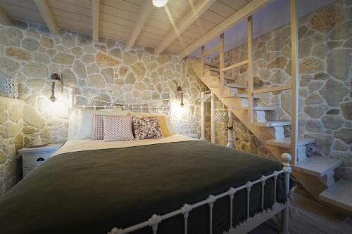 a bedroom with a bed and a stone wall at TheHouse1905 in Parga