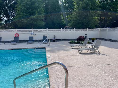 a swimming pool with chairs and a fence at La Quinta by Wyndham Danbury in Danbury