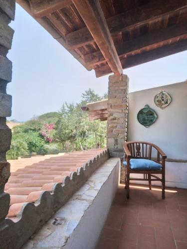 a chair sitting on a porch with a stone wall at La Dea Madre in Stintino