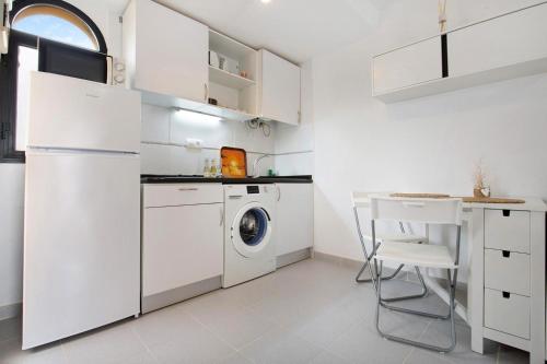 a white kitchen with a washing machine and a table at Apartamento Vista Piscina o Terraza, Wifi GRATIS in Costa Calma