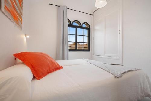 a white bedroom with an orange pillow on a bed at Apartamento Vista Piscina o Terraza, Wifi GRATIS in Costa Calma