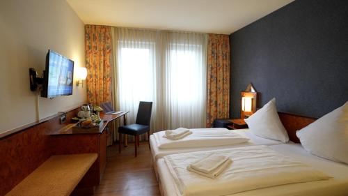 a hotel room with two beds and a desk at Hotel Miramar am Römer in Frankfurt
