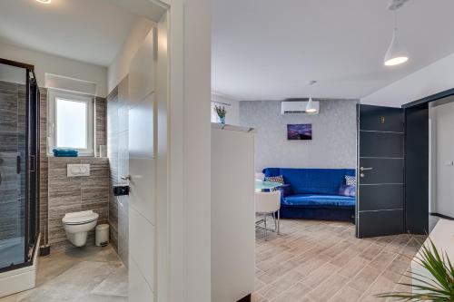 a bathroom with a toilet and a blue couch at Oliva Vallis Apartments in Zadar
