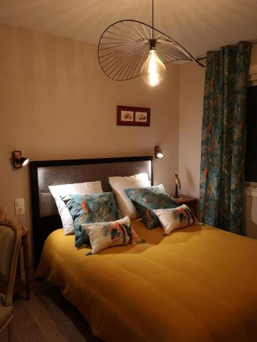 une chambre avec un lit avec des oreillers dessus dans l'établissement La maison du bonheur, à Port-en-Bessin-Huppain