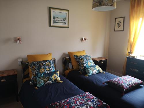 um quarto com duas camas com almofadas em La maison du bonheur em Port-en-Bessin-Huppain