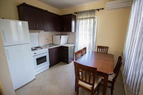 a kitchen with a table and a white refrigerator at Parea Kalamitsi in Kalamitsi