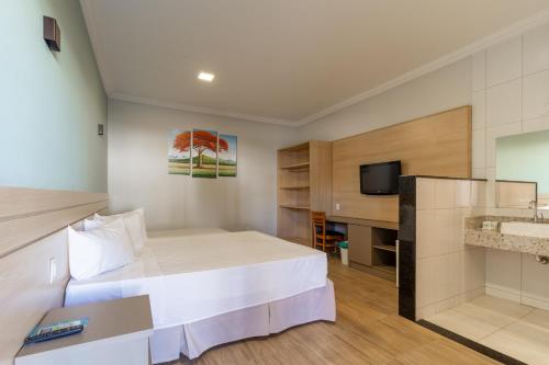 a hotel room with a bed and a tv at Porto Mar Hotel in Porto Seguro