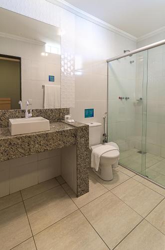 a bathroom with a toilet and a sink and a shower at Porto Mar Hotel in Porto Seguro