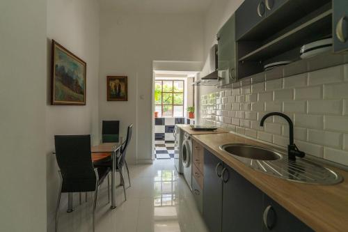 a kitchen with a sink and a table with chairs at Sleep Hostel in Niš