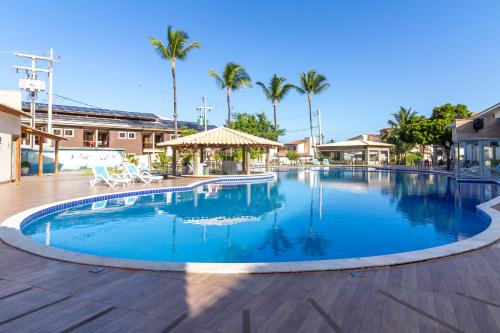 una gran piscina con palmeras en el fondo en Porto Mar Hotel, en Porto Seguro