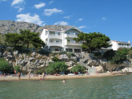 a large white house on a hill next to a beach at Apartments Agava-Mirjana in Omiš