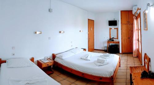 a room with two beds and a table and a tv at Philoxenia Hotel in Skala Prinou