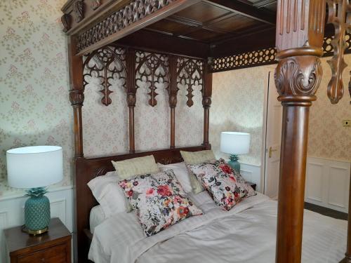 a bedroom with a wooden canopy bed with pillows at Stone Court House in Maidstone