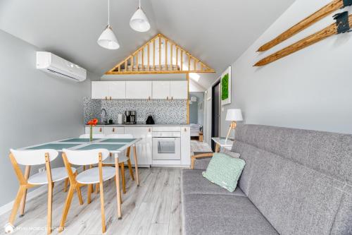 a kitchen and living room with a couch and a table at Holiday Hill Karpnki, Sauna, Domek Hygge-balia, Domek Lagom-jacuzzi in Karpniki