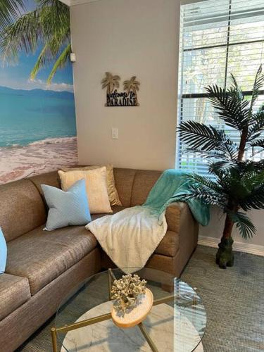 a living room with a couch and a palm tree at Island Breeze - 1BR/ Medical Center/ NRG/Galleria/Downtown in Houston