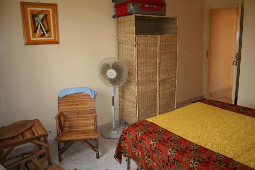 a bedroom with a bed and a fan and a chair at Auberge Keur Diame in Dakar
