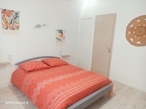 1 dormitorio con 1 cama con edredón de naranja en Le petit Cosy en Saint-Laurent-de-la-Salanque