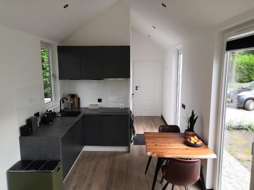 a kitchen with black cabinets and a wooden table at Huisje Bloemendal in Balkbrug