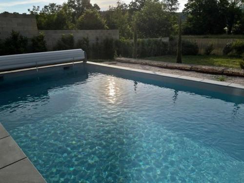 Una piscina de agua azul con un banco. en Gîte calme au bord de l'Ouche., en Fleurey-sur-Ouche