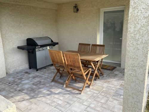 una mesa con sillas y una parrilla en el patio en Gîte calme au bord de l'Ouche., en Fleurey-sur-Ouche