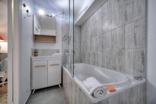 une salle de bain blanche avec une baignoire et une douche dans l'établissement IMMOGROOM -  Vue mer - Piscine - Terrasse - Parking - Au Calme, à Cannes