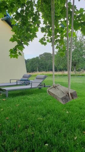 a swing in the grass with two chairs and a building at Le Grand Marguit*** sur la Côte Basco-Landaise in Tarnos