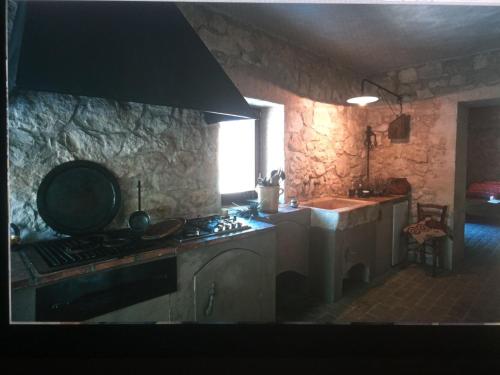 a stone kitchen with a stove and a sink at La pietra in Roccamorice