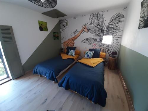 two beds in a room with a mural of a giraffe at La maison d Eugene in Clermont-Créans