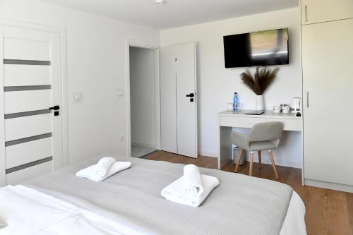 a white bedroom with a bed and a desk at Apartamenty Modrzewiowa Zator in Piotrowice
