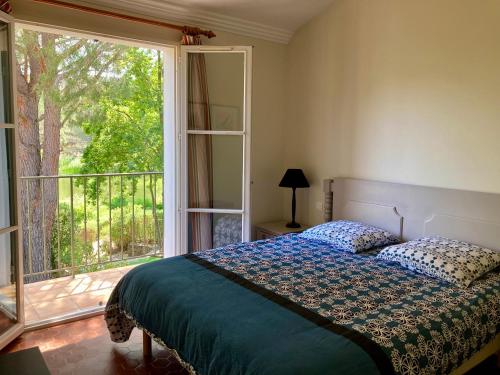 een slaapkamer met een bed en een groot raam bij Maison 20 du Lac Les Restanques in Grimaud