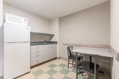 a kitchen with a white refrigerator and a table and chairs at Residence & Conference Centre - Hamilton in Hamilton