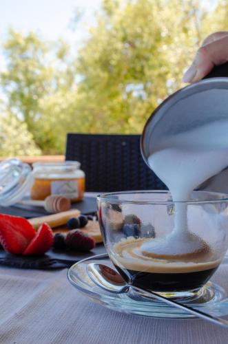 a person is pouring milk into a cup of coffee at La Minditta in San Teodoro
