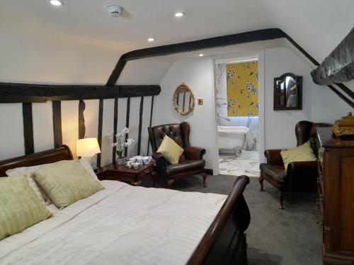 a bedroom with a bed and two chairs and a tub at Stone Court House in Maidstone
