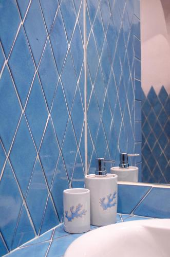 a blue tiled bathroom with three toilets on a tub at La Minditta in San Teodoro