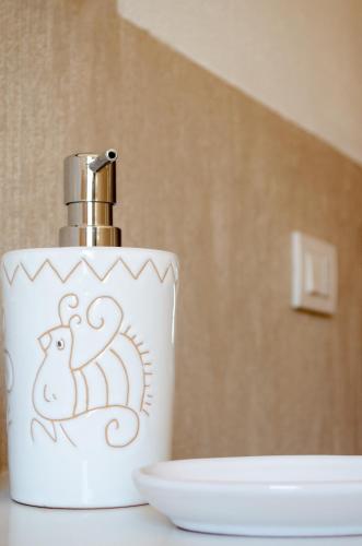 a white soap container with a spider on it next to a sink at La Minditta in San Teodoro