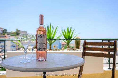 a bottle of wine and two wine glasses on a table at Nesto Athens Airport in Spáta