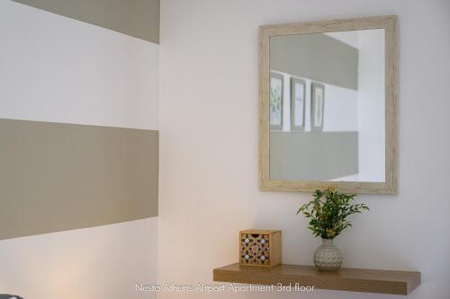 a mirror on a wall next to a table with a plant at Nesto Athens Airport in Spáta
