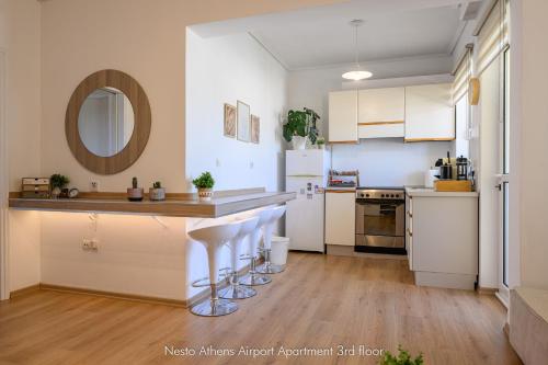 a kitchen with white cabinets and a counter with bar stools at Nesto Athens Airport in Spáta