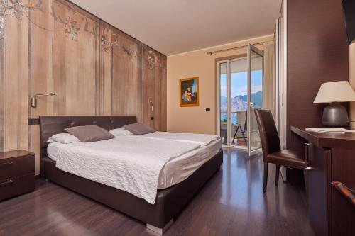 a bedroom with a bed and a desk and a window at Hotel Villa Smeralda in Malcesine