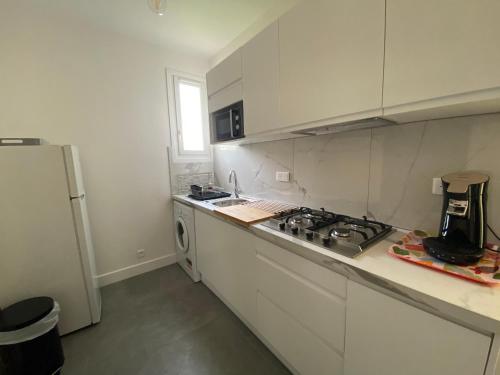 Il comprend une cuisine blanche équipée d'une cuisinière et d'un réfrigérateur. dans l'établissement Appartement calme avec terrasse proche du centre ville et de la mer, parking, internet, à Bastia