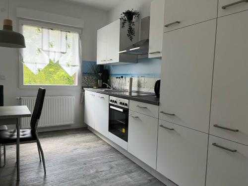 uma cozinha com armários brancos, uma mesa e uma janela em Heimathafen Crange em Herne