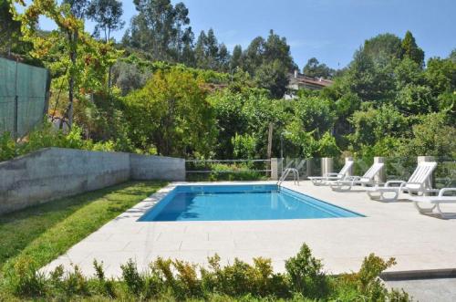 a swimming pool in a yard with lounge chairs around it at Casa Varanda do Gerês by Gerês Casas in Terras de Bouro