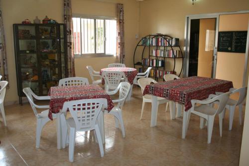 a dining room with tables and white chairs at Auberge Keur Diame in Dakar