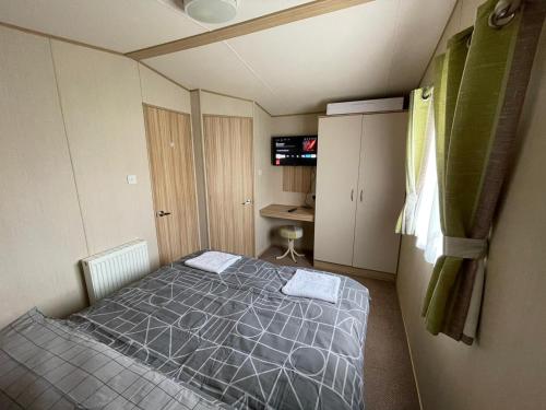 a bedroom with a bed in a small room at Holiday Park Caravan Fluffy in Harts Holiday Park in Leysdown-on-Sea