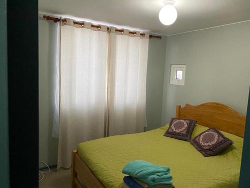 a bedroom with a green bed and a window at Condominio Espacio Urbano II in La Serena
