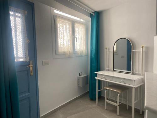 bagno con lavandino, specchio e porta blu di BIANCO BLUE a Città di Tinos