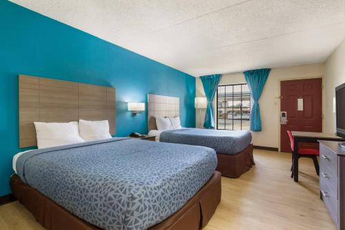 Habitación de hotel con 2 camas y paredes azules en One life studio and suites, en Evansville