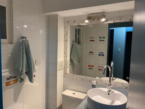 a bathroom with a sink and a toilet and a mirror at Condominio Espacio Urbano II in La Serena